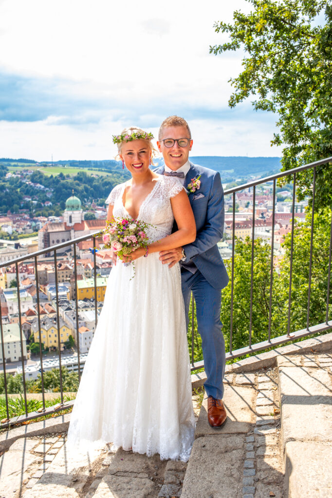 Fröhliches Brautpaar vor historischer Kulisse der Veste Oberhaus, fotografiert von Kosta Mücke.