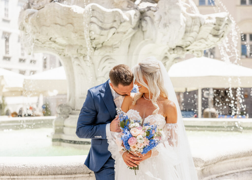 Brautpaar in Passau am Wittelsbacherbrunnen – romantisches Hochzeitsfoto mit Blumenstrauß