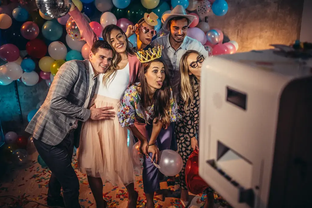 Gäste feiern vor der Fotobox auf einer Hochzeit in Passau und haben Spaß mit Accessoires und Ballons