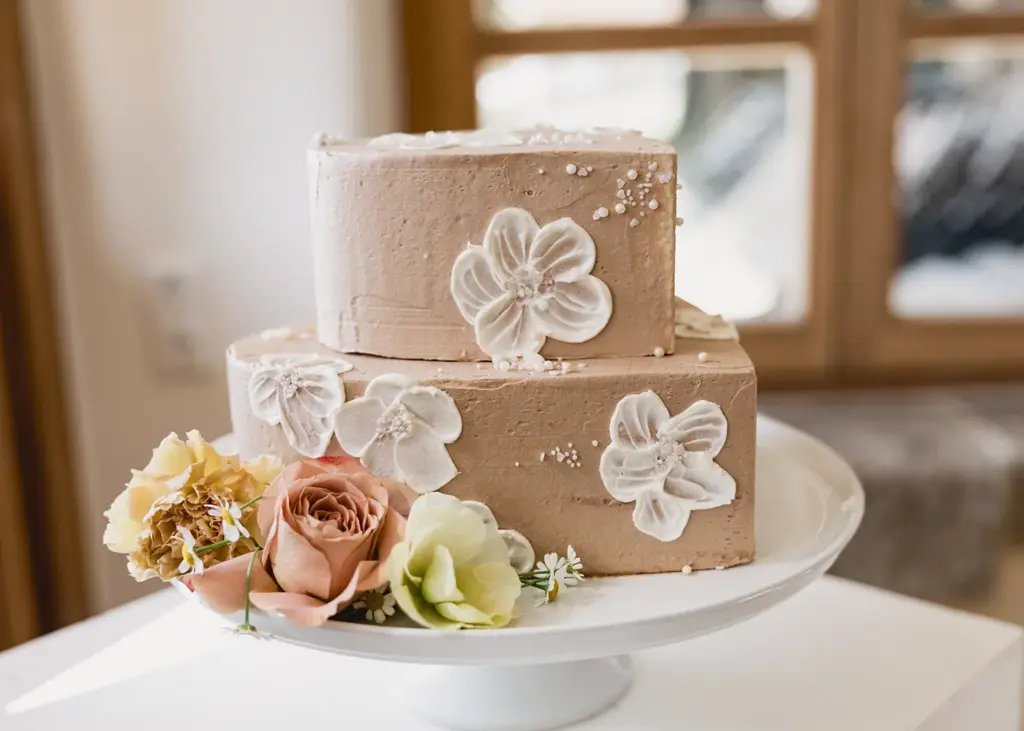 Zweistöckige Hochzeitstorte mit cremigem Finish und Blumenverzierung am Grandsberger Hof.